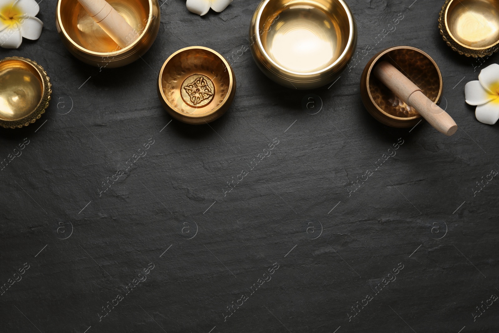 Photo of Flat lay composition with golden singing bowls on black table. Space for text