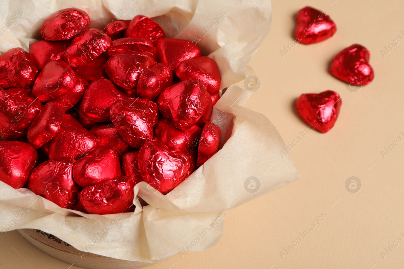 Photo of Beautiful heart shaped chocolate candies in box on beige background, above view with space for text