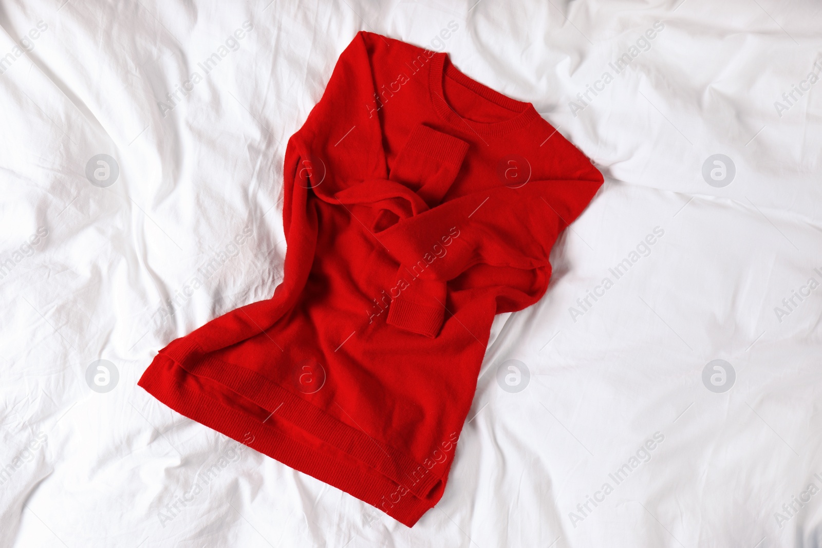 Photo of Red cashmere sweater on white fabric, top view