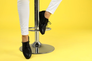 Photo of Woman in stylish shoes and bar stool on color background, closeup. Space for text