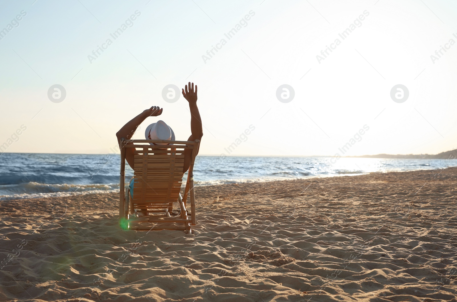 Photo of Young man relaxing in deck chair on beach near sea