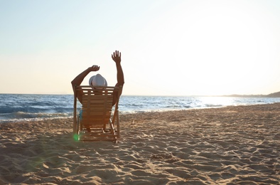 Photo of Young man relaxing in deck chair on beach near sea