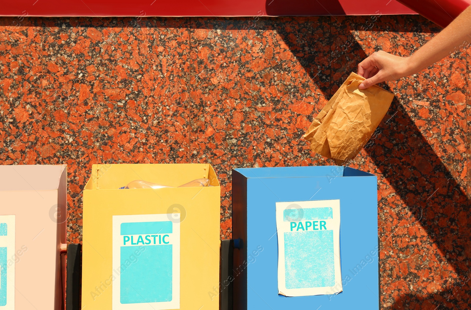 Photo of Woman throwing paper into recycling bin outdoors, closeup