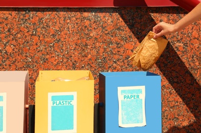 Photo of Woman throwing paper into recycling bin outdoors, closeup