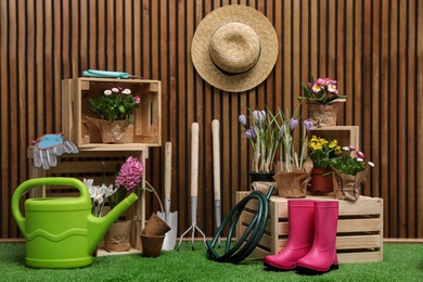 Photo of Composition with different gardening tools on artificial grass at wooden wall