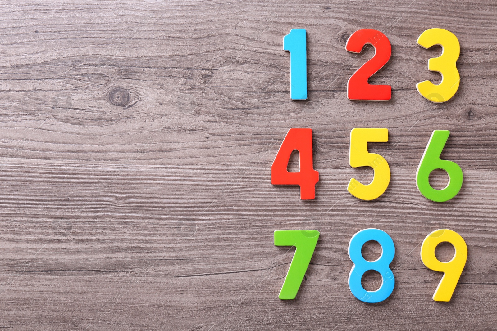 Photo of Colorful numbers on wooden school desk, flat lay. Space for text