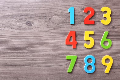 Photo of Colorful numbers on wooden school desk, flat lay. Space for text