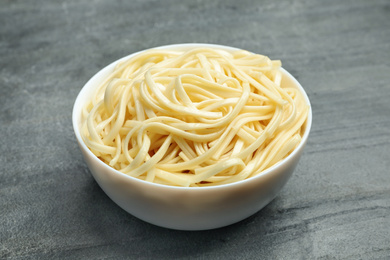 Photo of Tasty cooked rice noodles on grey table, closeup