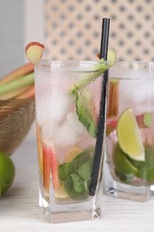 Tasty rhubarb cocktail with lime on white wooden table, closeup