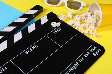 Photo of Clapperboard, popcorn and 3D glasses on color background, closeup