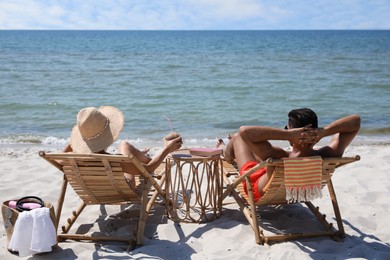 Photo of Couple resting in wooden sunbeds on tropical beach