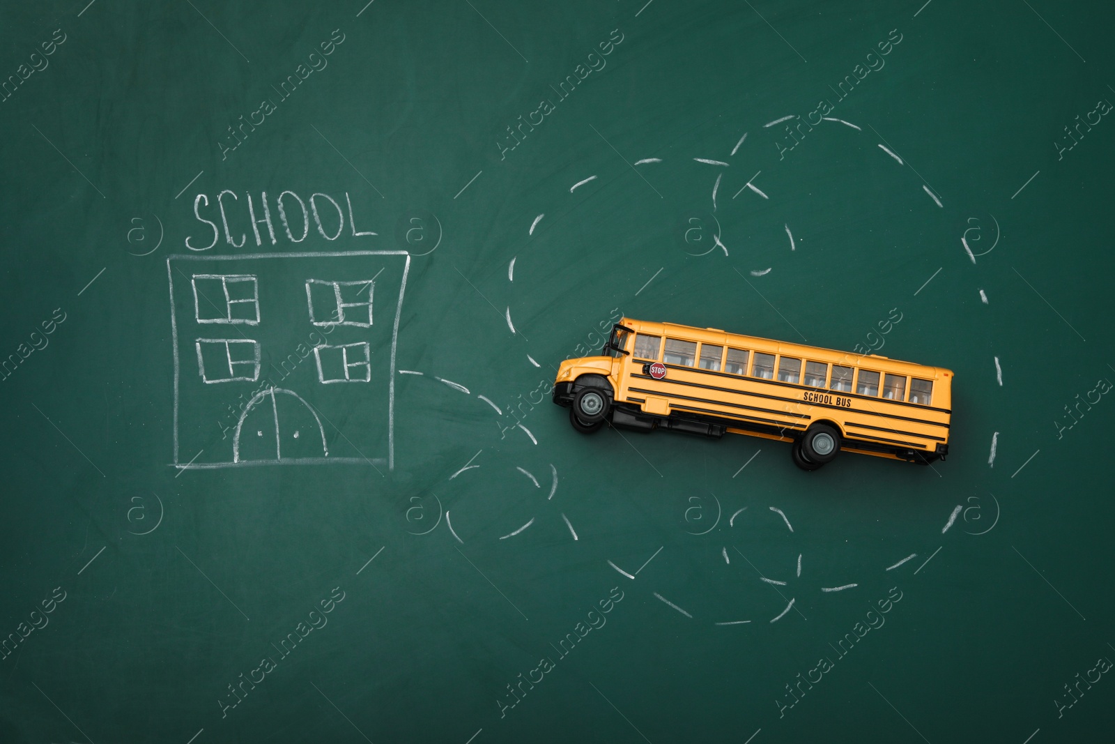 Photo of Yellow bus and drawing of school on chalkboard, top view. Transport for students