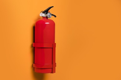 Red fire extinguisher on orange background. Space for text