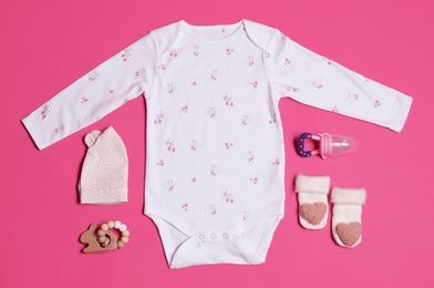 Flat lay composition with baby clothes and accessories on pink background