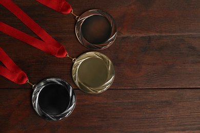 Gold, silver and bronze medals on wooden background, flat lay. Space for design