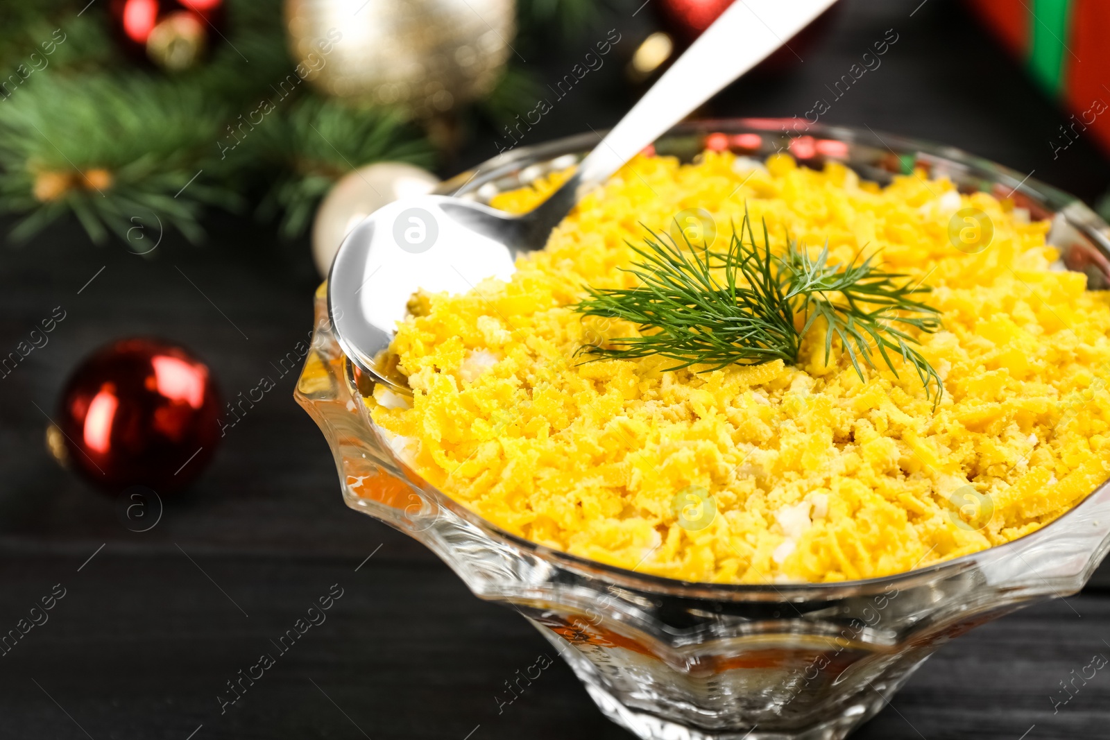 Photo of Traditional russian salad Mimosa and festive decor on dark wooden table, closeup