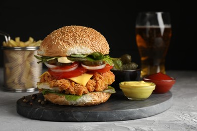 Delicious burger with crispy chicken patty and sauces on grey table