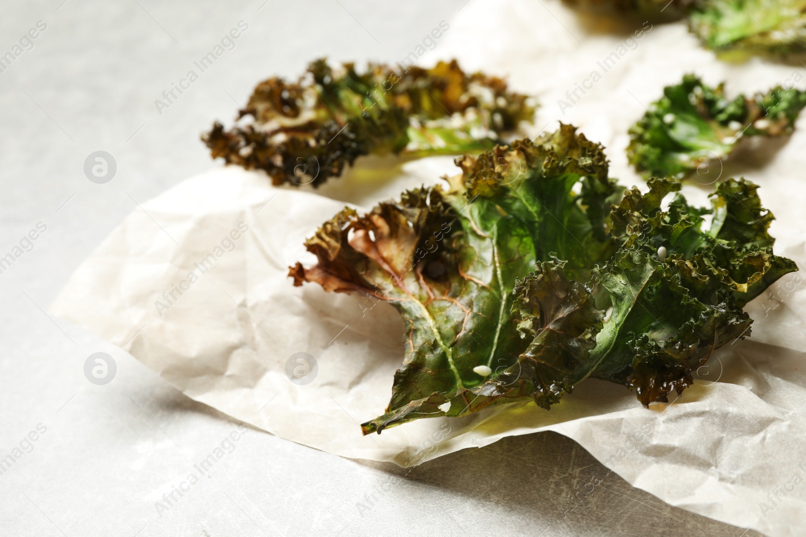 Photo of Tasty baked kale chips on grey table, closeup