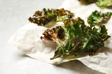 Tasty baked kale chips on grey table, closeup