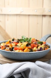 Photo of Delicious ratatouille in frying pan on board, space for text