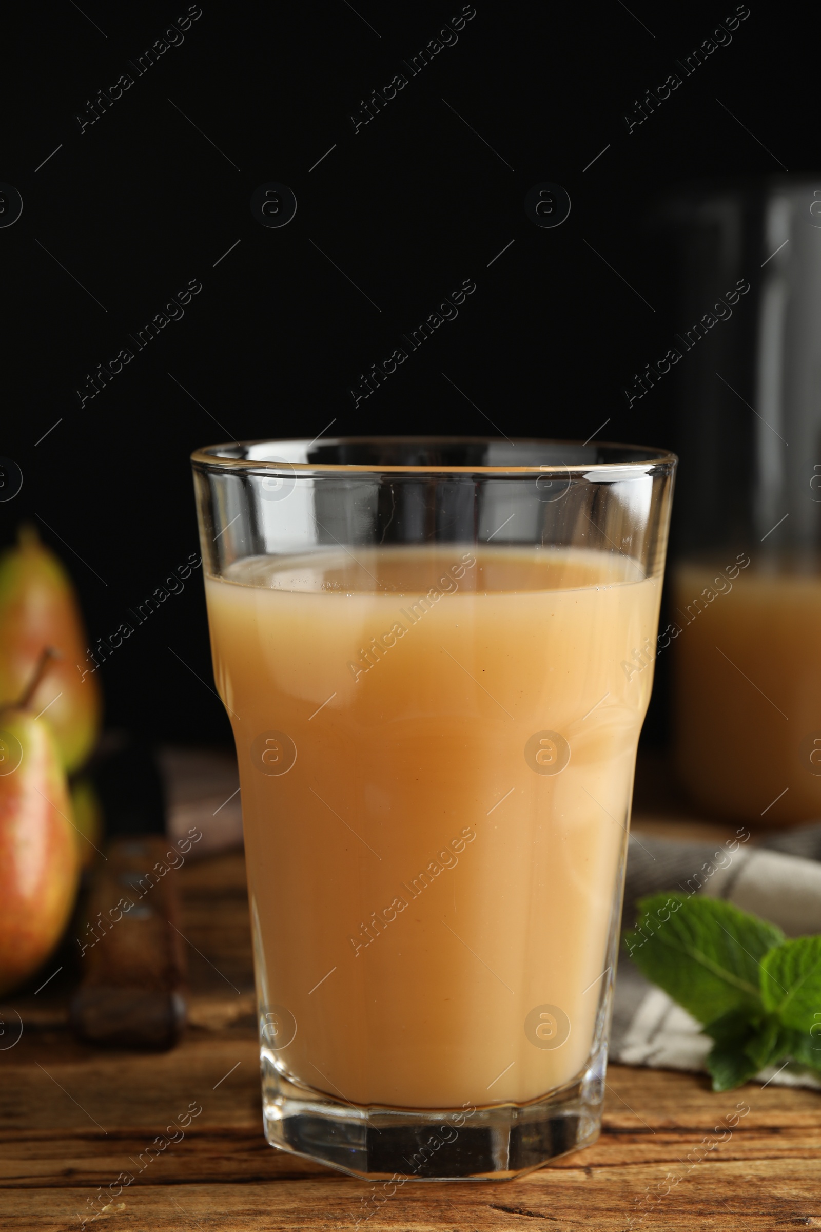 Photo of Fresh pear juice in glass on wooden table, closeup