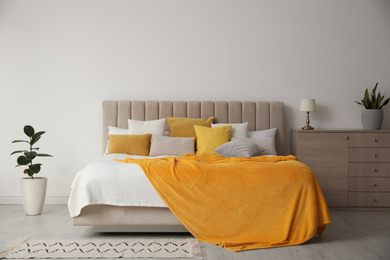 Photo of Stylish bedroom interior with soft yellow pillows and blanket