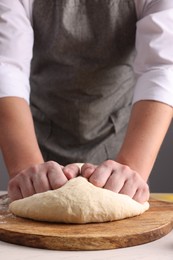 Man kneading dough at white table, closeup
