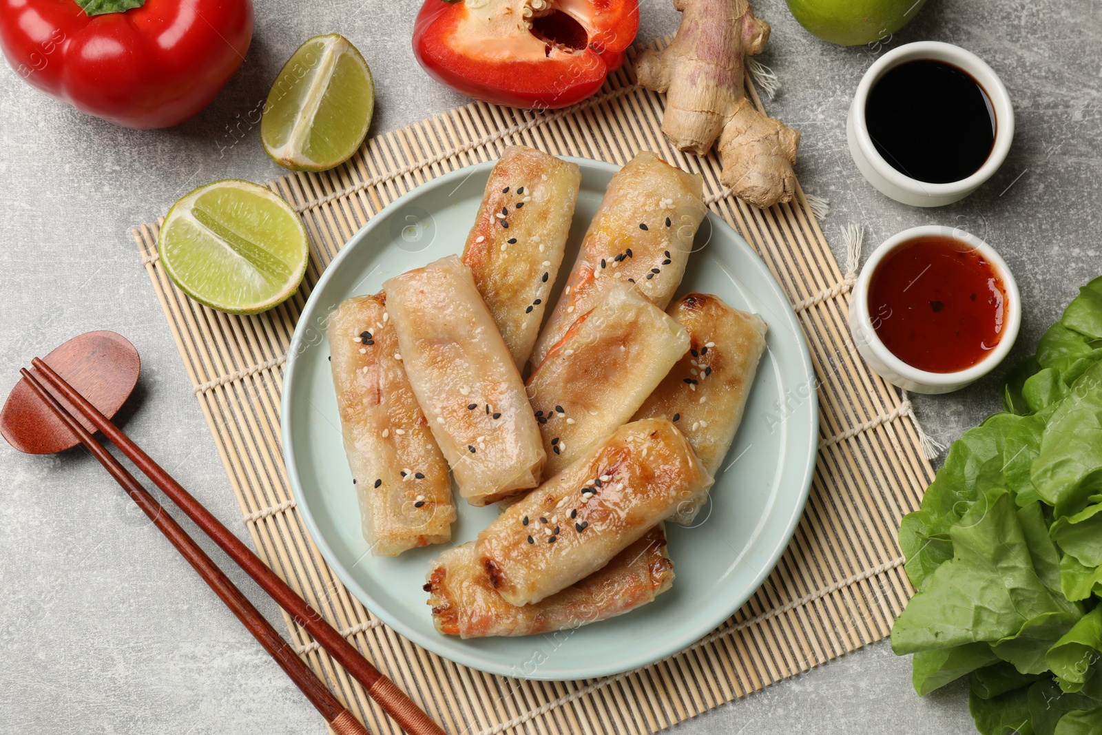 Photo of Tasty fried spring rolls served on gray table, flat lay