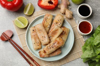 Photo of Tasty fried spring rolls served on gray table, flat lay