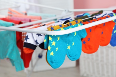 Different colorful socks on drying rack against blurred background, closeup