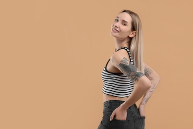Photo of Portrait of beautiful tattooed woman on beige background, space for text