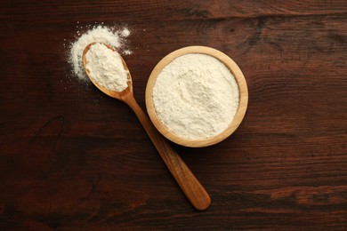 Photo of Baking powder in bowl and spoon on wooden table, top view