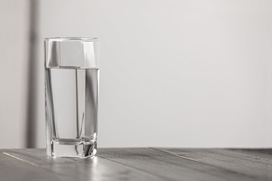 Photo of Glass of pure water on wooden table indoors, space for text