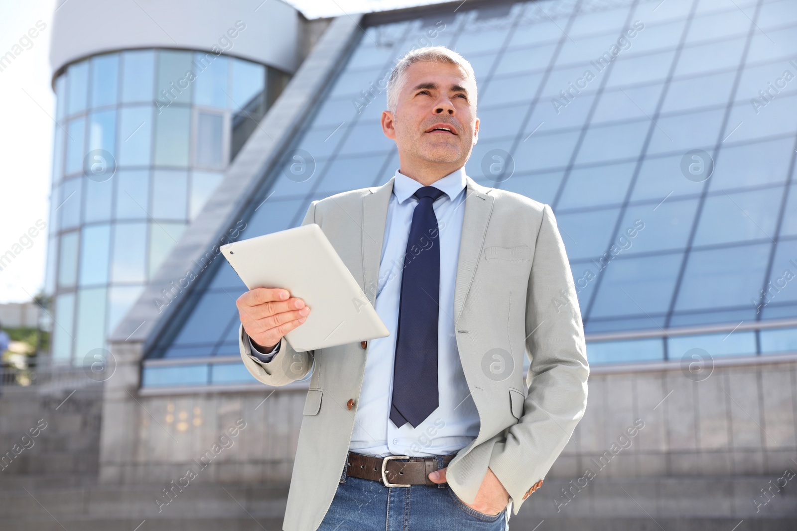 Photo of Portrait of handsome businessman with tablet in city