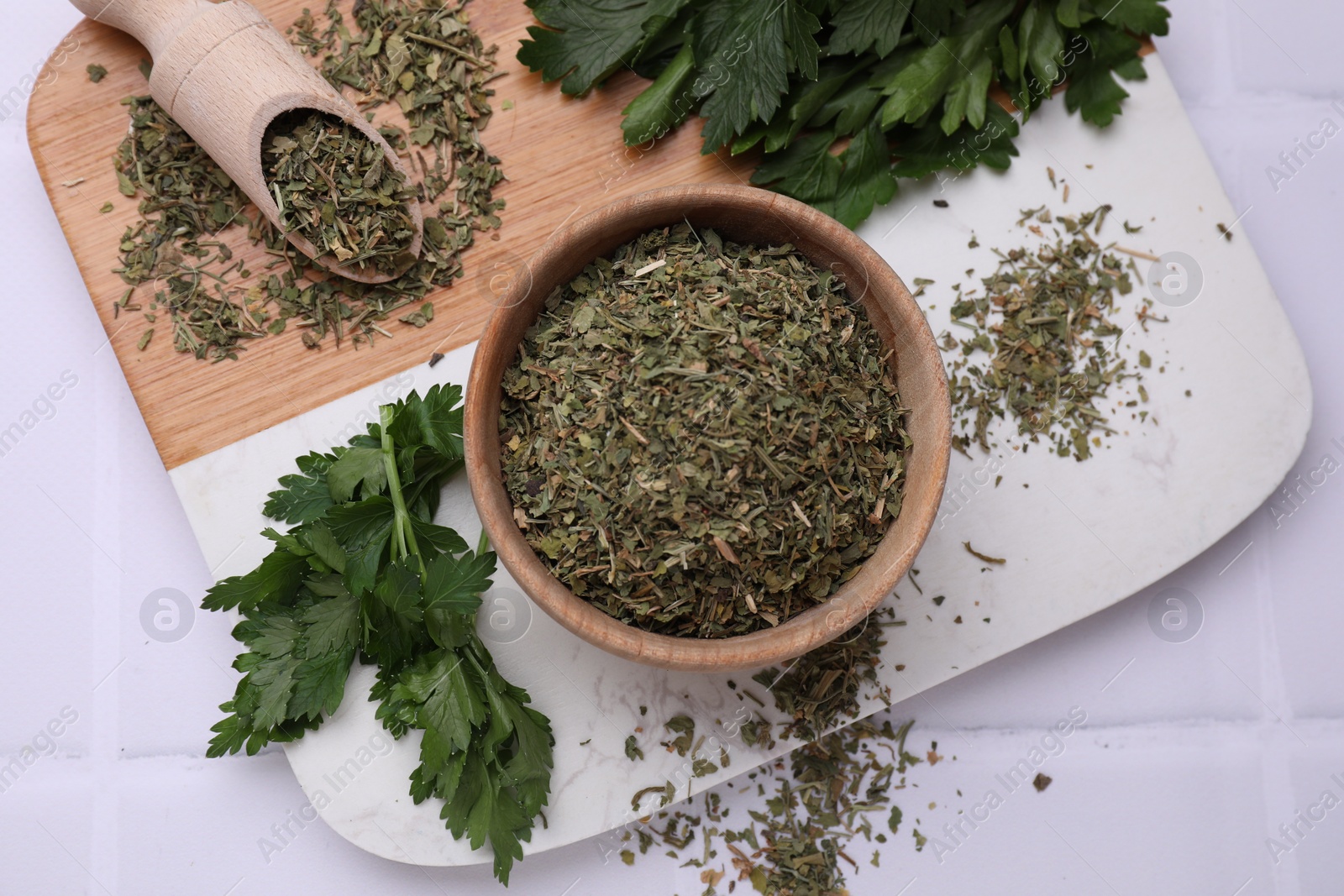 Photo of Dried parsley and fresh leaves on white tiled table, flat lay