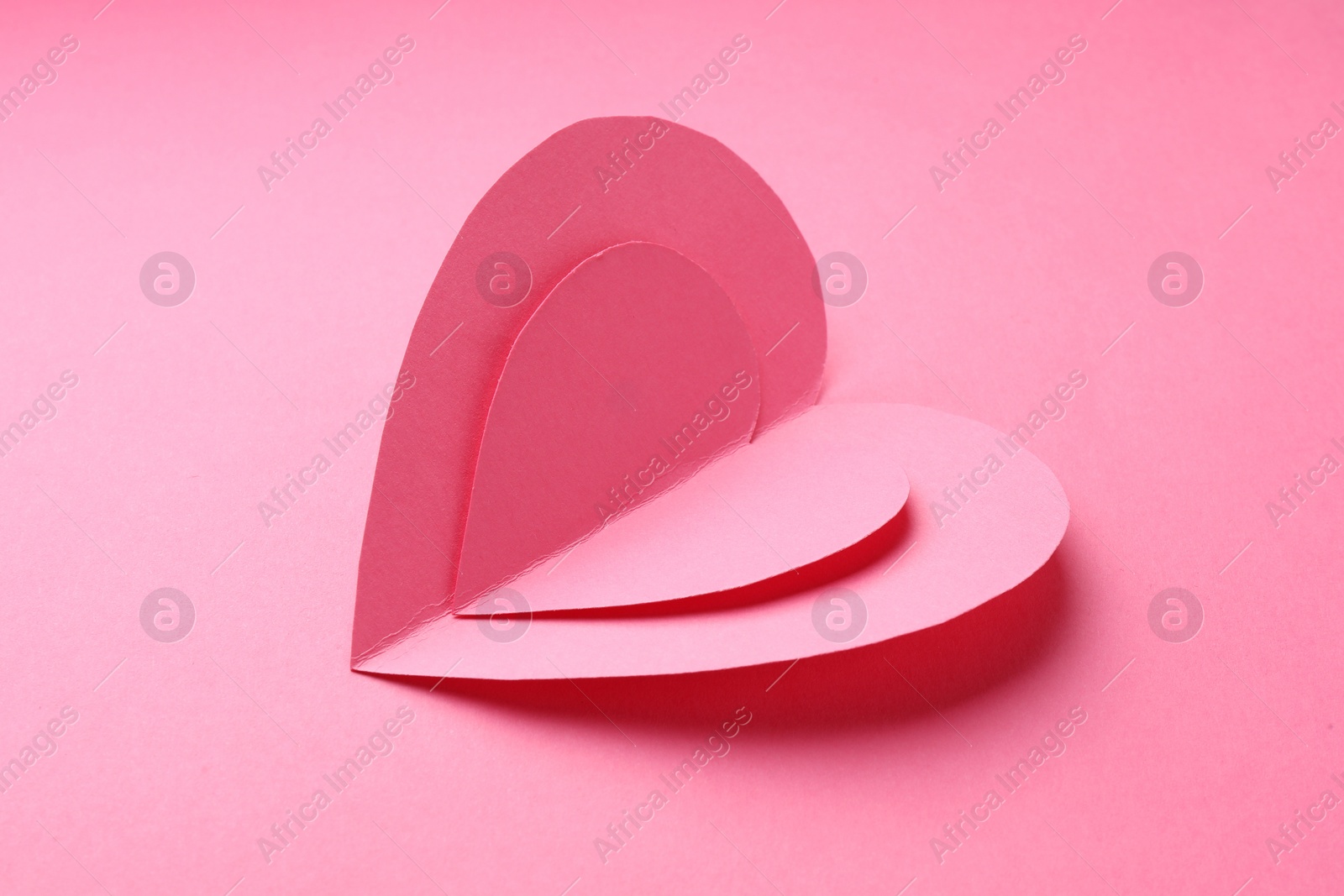 Photo of Two paper hearts on pink background, closeup