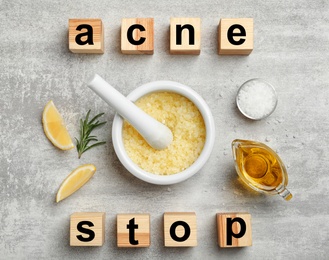 Wooden cubes with phrase "Stop acne" and homemade effective problem skin remedies on grey background, flat lay