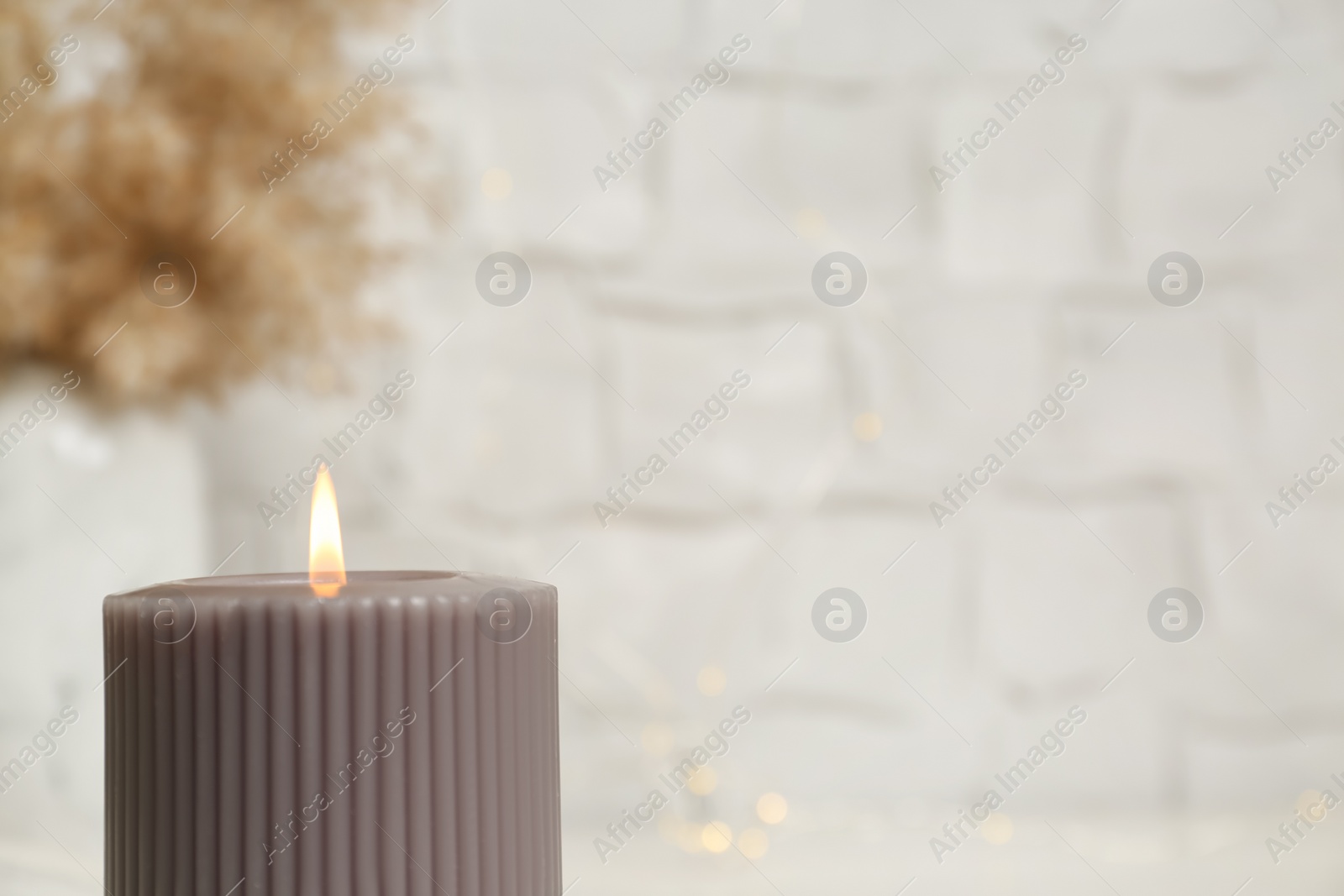 Photo of Burning candle on blurred background, closeup. Space for text