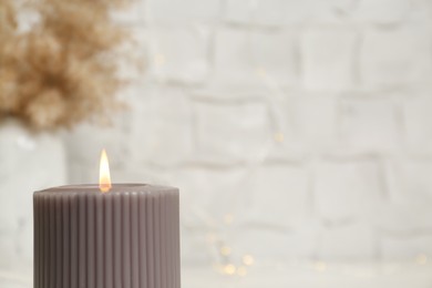 Photo of Burning candle on blurred background, closeup. Space for text