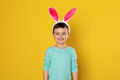 Portrait of little boy in Easter bunny ears headband on color background