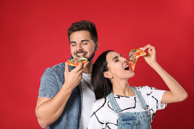 Photo of Emotional young couple with pizza on red background