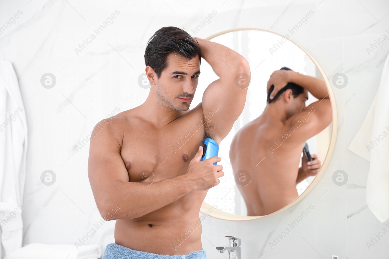 Photo of Handsome young man applying deodorant in bathroom