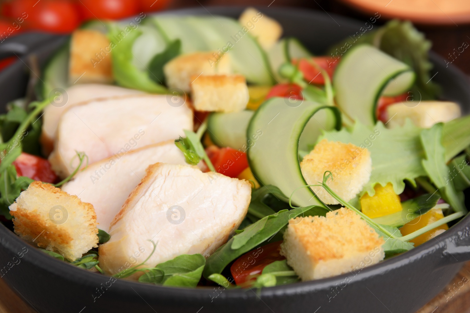 Photo of Delicious salad with croutons, chicken and vegetables served on table, closeup