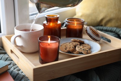 Breakfast tray with burning candles near window indoors