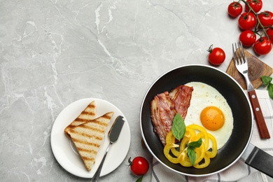 Tasty breakfast with fried egg on grey marble table, flat lay. Space for text