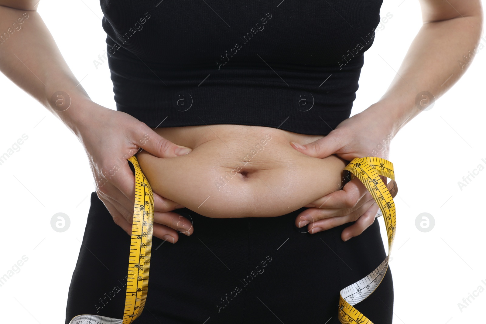 Photo of Woman with measuring tape touching belly fat on white background, closeup. Overweight problem