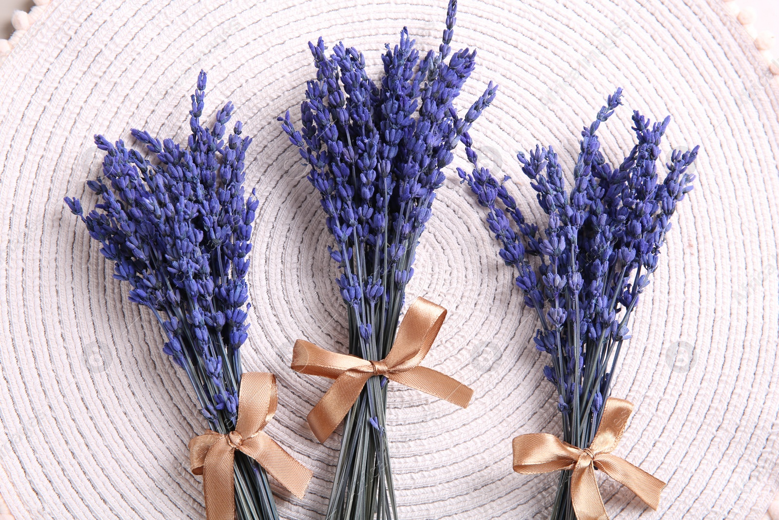 Photo of Bouquets of beautiful preserved lavender flowers on white cotton place mat, flat lay