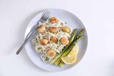Photo of Delicious scallop pasta with asparagus, green onion and lemon served on white table, top view