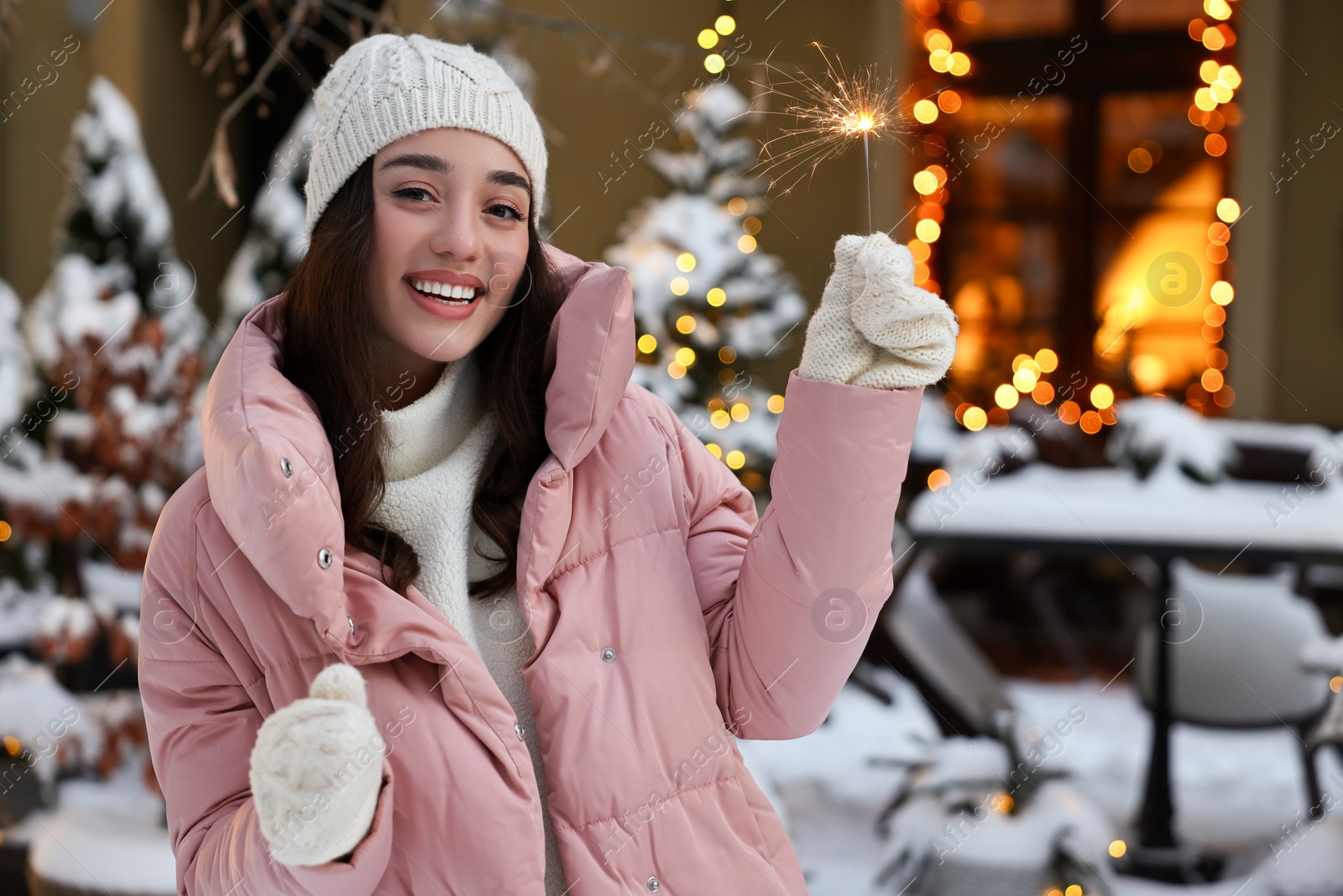 Photo of Portrait of smiling woman with burning sparkle on snowy city street. Space for text