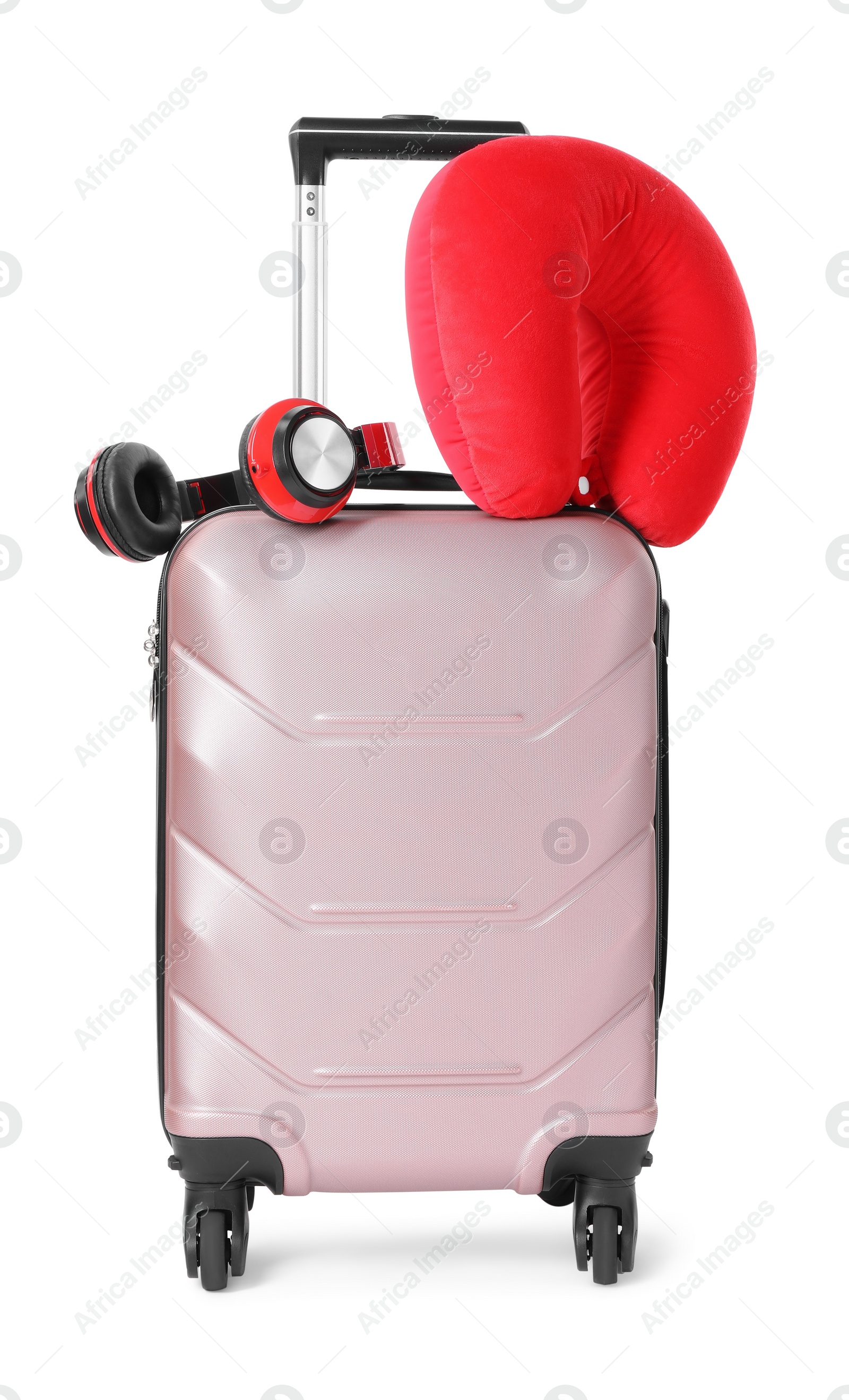 Photo of Red travel pillow and headphones on suitcase against white background